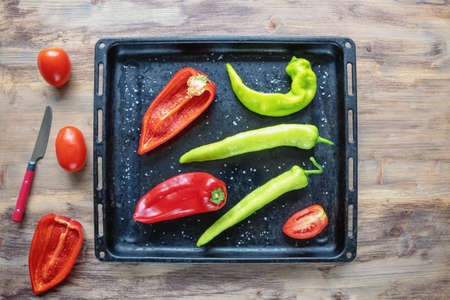 Bright vegetables on black  baking sheet.  Green and red peppers, tomatoes.  Rustic table.  Flat lay, copy spaceの写真素材