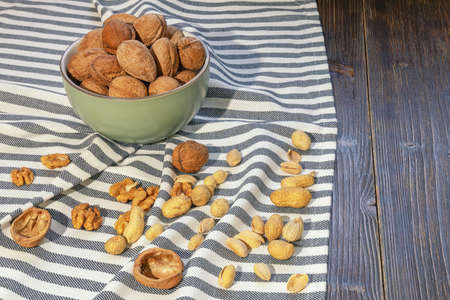Nuts on dark rustic table. Whole walnuts and kernels, pistachios, peanut. Copy spaceの写真素材