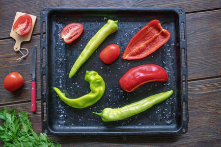 Vegetables. Tomatoes,  green and red peppers - on black  baking sheet. Flat lay, copy spaceの写真素材