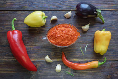 Balkan cuisine. Ajvar, delicious condiment of pepper, eggplants, garlic - on dark rustic tableの写真素材