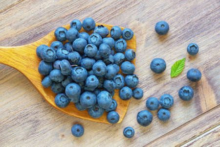 Fresh ripe blueberries in wooden spoon on rustic table. Free space for textの写真素材