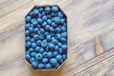 Fresh ripe whortleberries in cardboard box from market on rustic table. Flat lay. Copy spaceの写真素材