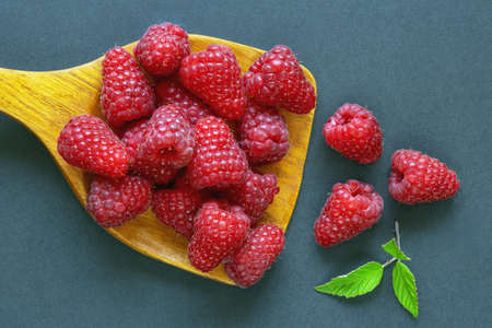 Berries. Raspberry on wooden spoon on dark paper background. Flat lay, free space for textの写真素材