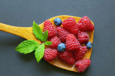 Raspberry in wooden spoon on dark background.  Flat lay, copy spaceの写真素材