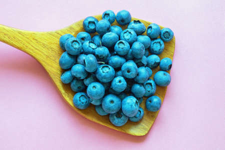 Bog whortleberries in wooden spoon. Free space for textの写真素材