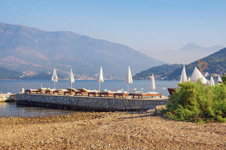 Beautiful Mediterranean landscape with beach umbrellas. Beach vacation concept.  Montenegro, Adriatic Sea.  View of Bay of Kotor near Tivat cityの写真素材