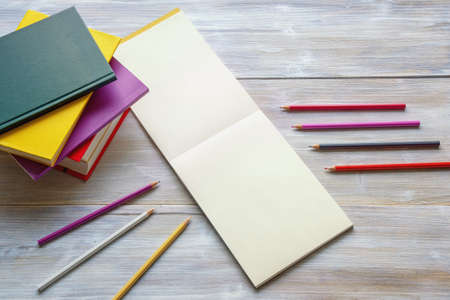Colored pencils, books and open sketchbook on rustic table. Free space for text or pictureの写真素材
