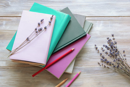 Dry flowers of lavender, colored pencils and stack of books on rustic table. Copy spaceの写真素材