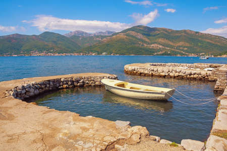 Beautiful Mediterranean landscape with fishing boat in small harbor. Montenegro, Adriatic Sea, Bay of Kotor.  Mandrac ( mandrach ) is dry stone jetty, cultural heritage in Kotor Bayの写真素材