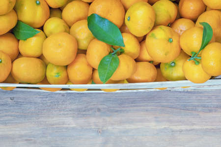 Fruits from market.  Fresh ripe tangerines in wooden crate on rustic table. Free space for textの写真素材