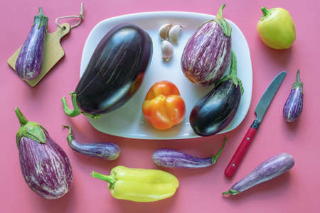 Different vegetables - eggplants and bell peppers -  on pink background. Flat layの写真素材