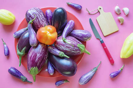Vegetables. Bell peppers and eggplants in red plate on pink background. Healthy and vegetarian food conceptsの写真素材