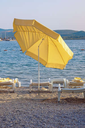 Beach vacation.  One yellow beach umbrella on coast of Kotor Bay on autumn day. Montenegro, Tivatの写真素材