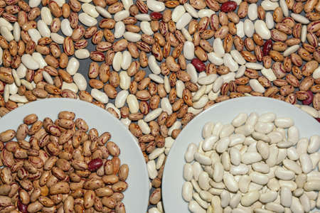Mixture of white and brown  haricot beans on black table. Sorting beans by gradeの写真素材
