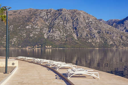 Autumn Mediterranean landscape. Montenegro, Adriatic Sea. Coast of Kotor Bay. Prcanj town embankment with chaise loungesの写真素材