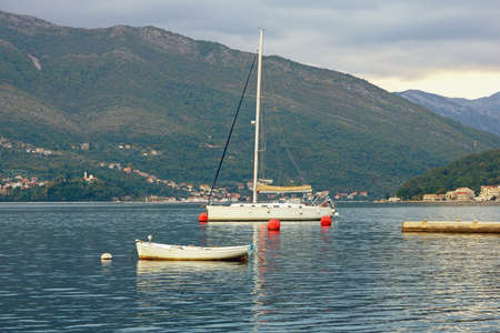 Overcast. Autumn Mediterranean landscape. Sailboat on water against mountains. Montenegro, Adriatic Sea. View of Bay of Kotor near Tivat cityの写真素材