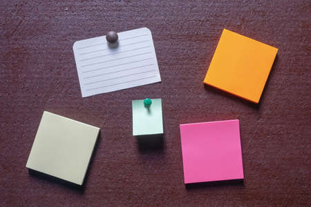 Colorful post it notes on dark brown board. Copy spaceの写真素材