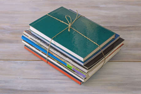Stack of different books and magazines tied with rope on rustic tableの写真素材