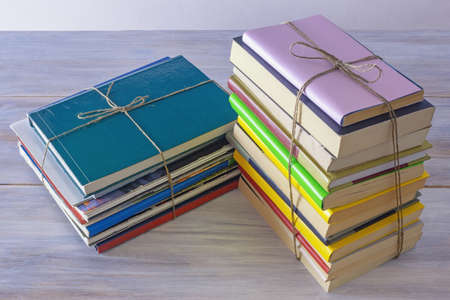Two stacks of different old books and magazines  tied with rope on rustic table.  Copy spaceの写真素材