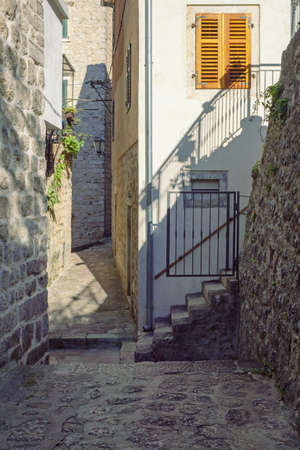 Montenegro. Narrow street of Old Town of Kotor on sunny winter day. Ancient buildings, steps.  Light and shadowsの写真素材
