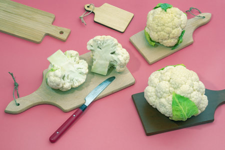 Fresh white cauliflower  and different cutting boards on pink backgroundの写真素材