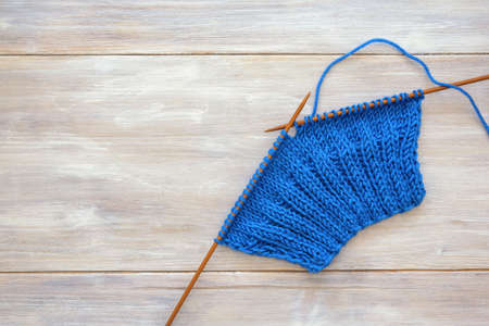 Hobby concept. Unfinished knitting with knitting needles on rustic table. Space for textの写真素材