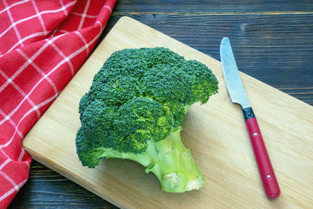 Flowering head of  broccoli on cutting board.  Dark rustic table, copy spaceの写真素材