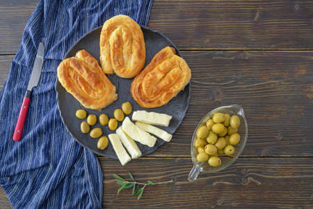 Balkan cuisine. Burek, filled pastry, popular national dish in Balkans. Olives and local soft white cheese. Rustic table, copy spaceの写真素材