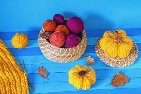 Autumn. Yellow knitted pumpkins, colorful balls of wool, autumn  leaves and unfinished knitting on...