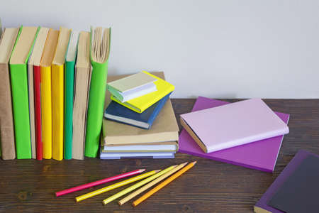 Different colorful books, notebooks and colored pencils on dark rustic table. Copy spaceの写真素材