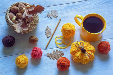 Autumn concepts. Colorful balls of wool, knitted pumpkin, autumn leaves and cup of coffee on rustic tableの写真素材