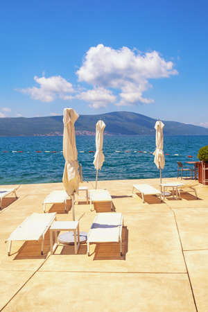 Summer beach vacation.  Chaise-lounges and beach umbrellas on coast of Kotor Bay.  Montenegro, Adriatic Sea, Tivatの写真素材
