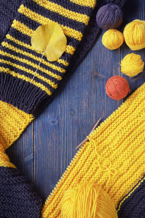 Hobbies and knitting concept. Yellow and brown knitting and balls of wool on dark rustic table. Copy spaceの写真素材