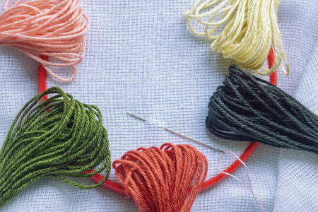Hobby concept. Red embroidery frame and colorful threads. Copy spaceの写真素材