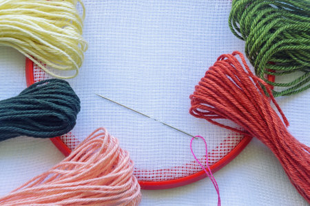 Hobby concept. Embroidery frame with canvas and colorful threads. Copy spaceの写真素材