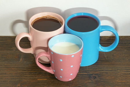 Three different ceramic mugs with different drinks - milk, coffee, fruit juice - on rustic tableの写真素材
