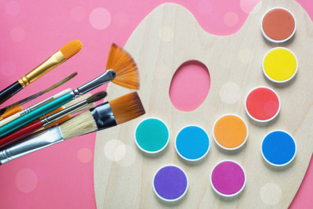 Different types of brushes on the background of a defocused palette with paintsの写真素材
