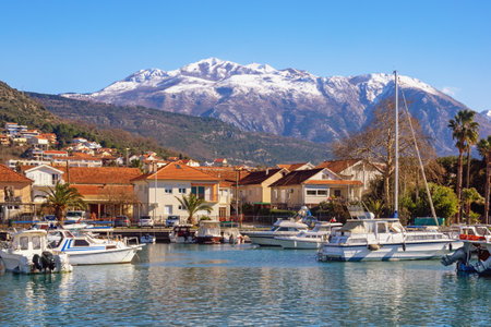 Beautiful winter Mediterranean landscape. Montenegro, Tivat city.  View of Marina Kalimanj on sunny day. Fishing boats in harbor. Snow-capped Lovcen mountainsの写真素材