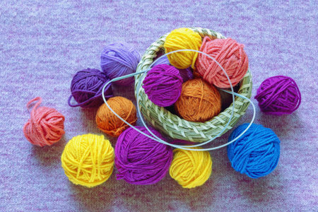 Hobbies and knitting concept.   Colorful balls of wool in small basket on knitted background. Copy...