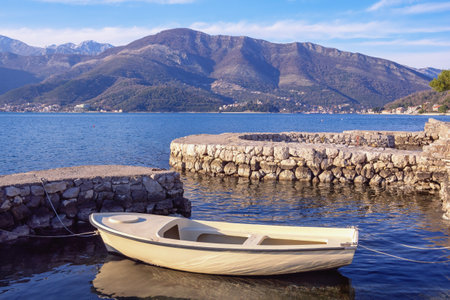 Beautiful winter Mediterranean landscape. White fishing boat in small stone jetty.  Montenegro, Kotor Bayの写真素材