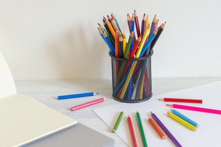 Pencil holder with colored pencils and sketch pads on rustic table. Copy spaceの写真素材