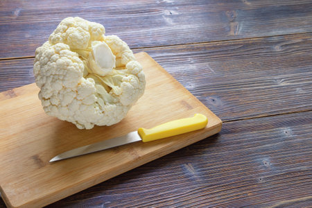 Fresh cauliflower head on cutting board on dark rustic table. Copy spaceの写真素材