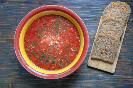 Ukrainian cuisine. Borscht, traditional red beetroot soup. Bread on cutting board. Dark rustic tableの写真素材