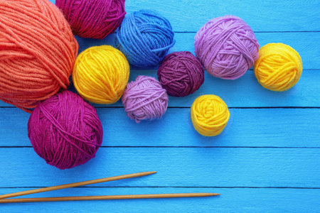 Hobbies and knitting concept. Bright colorful balls of wool and  knitting needles on blue rustic background. Copy spaceの写真素材