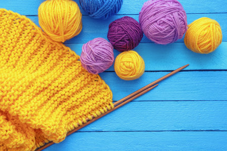 Knitting concept. Bright balls of wool and  knitting needles on blue rustic table. Copy spaceの写真素材