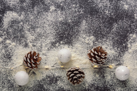 Christmas background. Pine cones and Christmas balls on black background and snow. Flat lay, copy spaceの写真素材
