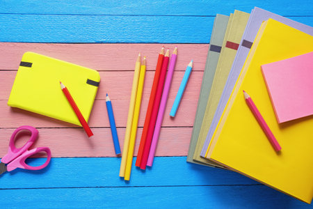 Stack of books, notepad, colored pencils on rustic table. Flat lay. Copy spaceの写真素材