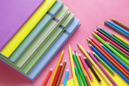 Stack of books and bright colored pencils on colored paper. Copy spaceの写真素材