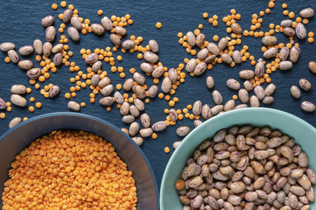 Sorting. Red lentils and brown beans on black table. Sorting legumes by grade at homeの写真素材