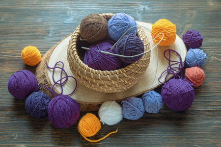 Hobby and knitting concept. Balls of wool and knitting needles in small basket on dark rustic tableの写真素材